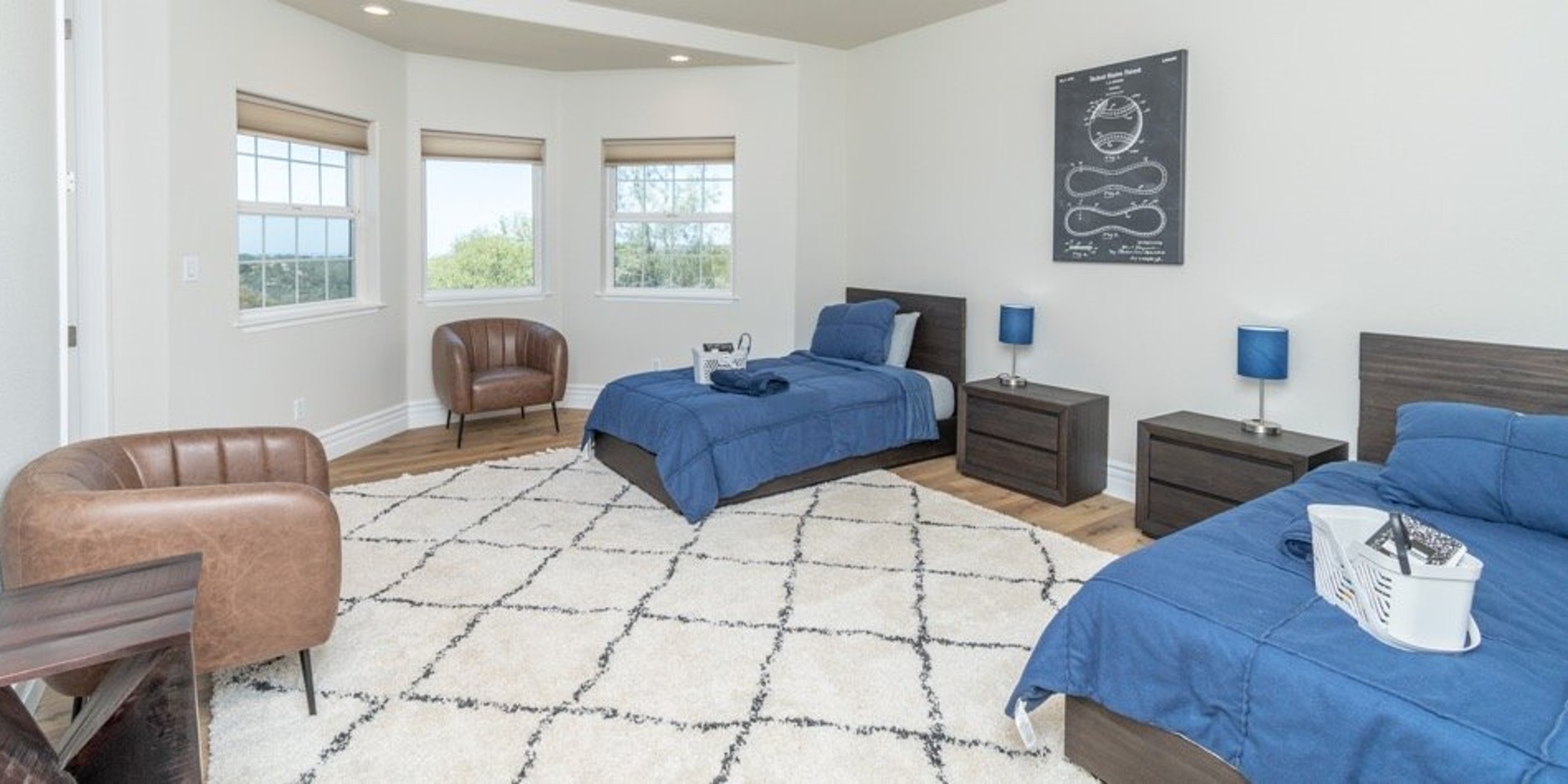 Bright shared bedroom with two twin beds and large corner windows.