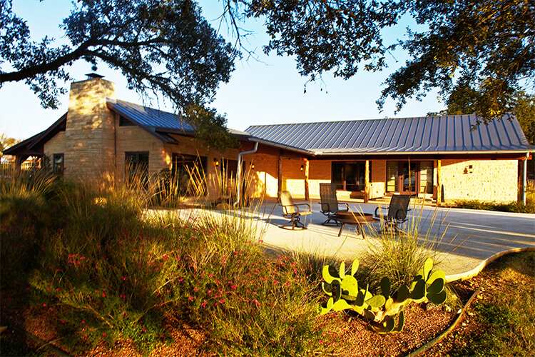 Patio area with chairs behind a stone cabin in natural light