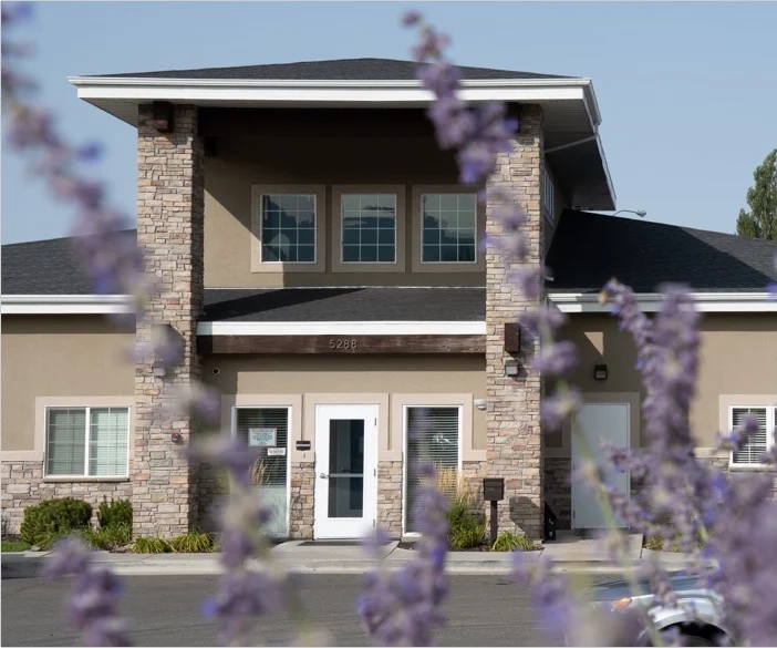 Two-story building with stone columns and purple flowers