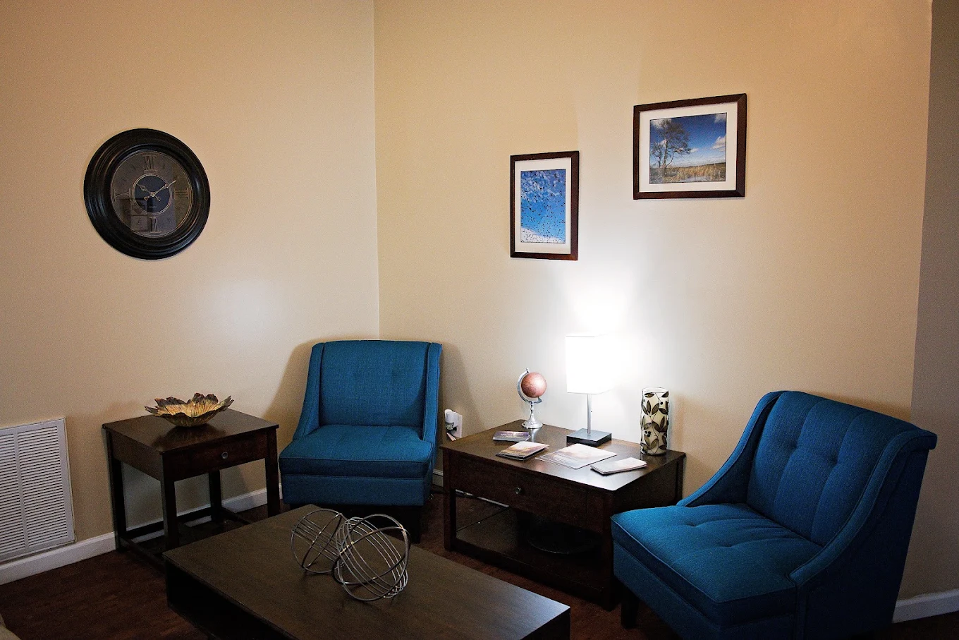 Quiet seating area with blue chairs, tables, and wall art
