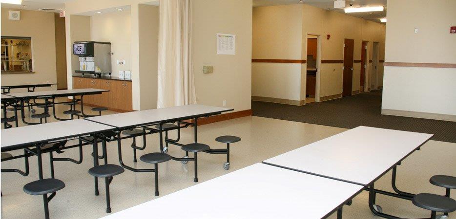 Cafeteria with long white tables and round stools
