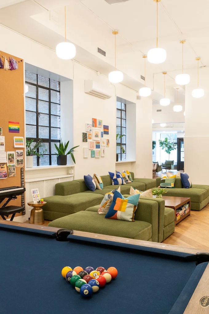 Recreation room with pool table, green sofas, and large windows