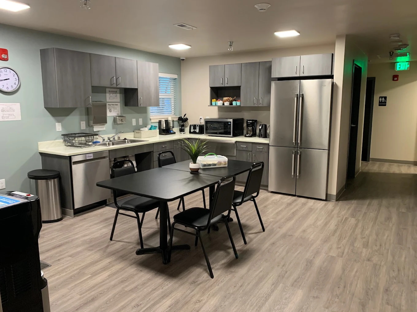 Modern kitchen space with stainless steel appliances, dining table, and cabinetry for communal use