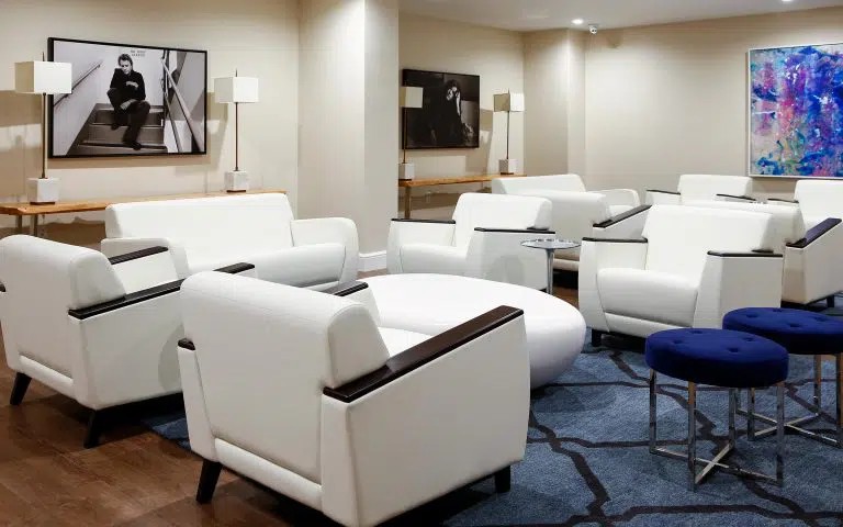 Lounge with white chairs, blue stools, and framed art.