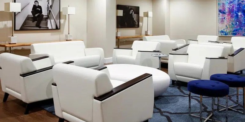  A sleek lounge area features contemporary white seating, modern artwork, and soft lighting, offering a comfortable and stylish place to relax.