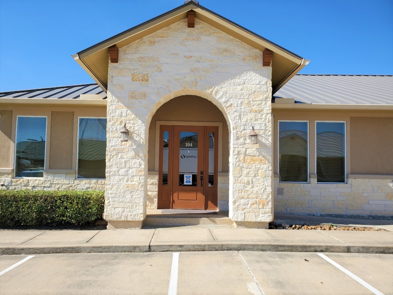 The exterior of Symetria Recovery with a stone entrance and glass doors.
