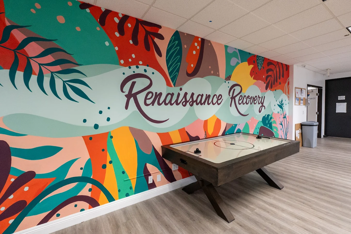 Air hockey table in front of colorful Renaissance mural