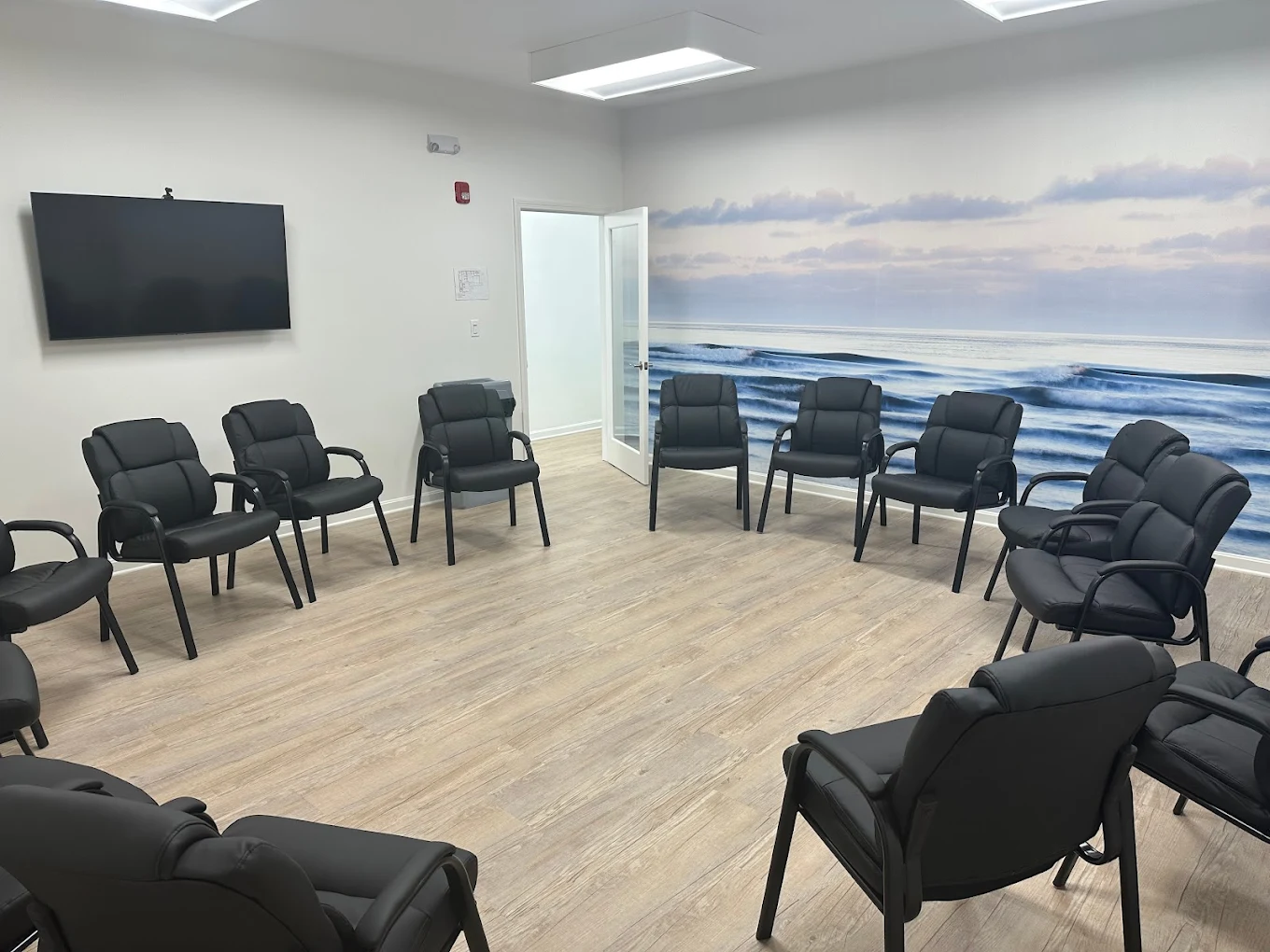 Group therapy room with circle of chairs and ocean mural