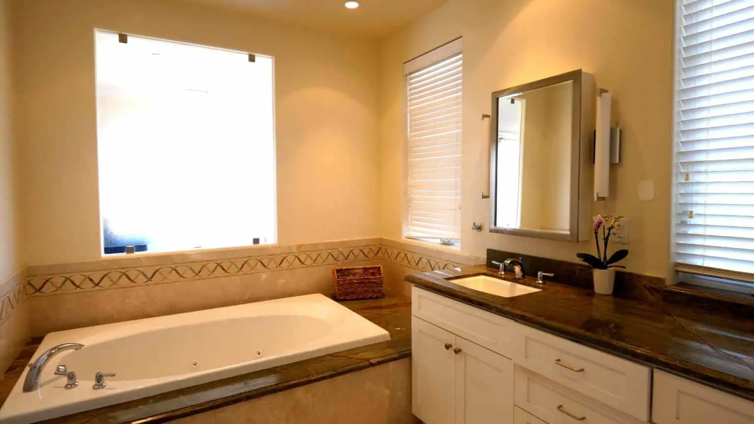 Bathroom with soaking tub, vanity, mirror, and large window