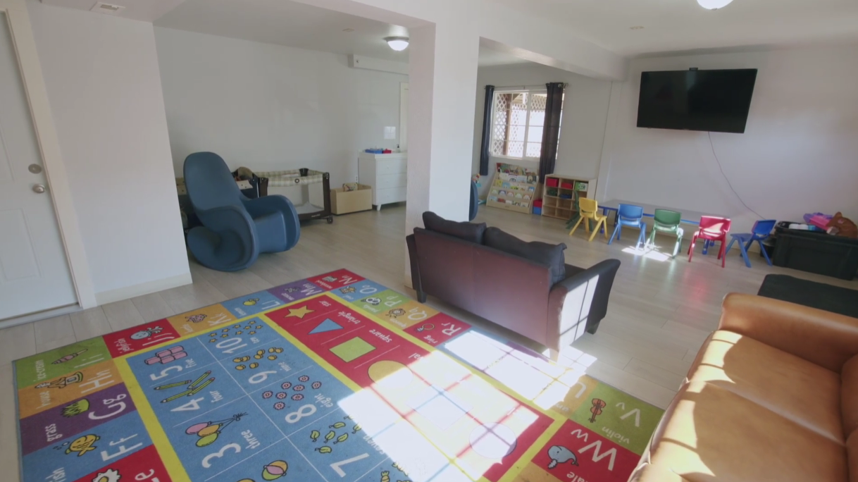Bright playroom with colorful rug, small chairs, and TV on wall