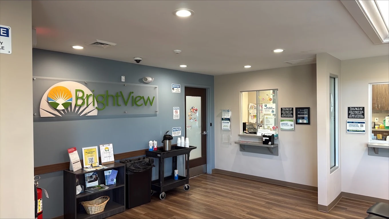 BrightView Health reception area with branded wall sign, service windows, informational materials, and wood-look flooring