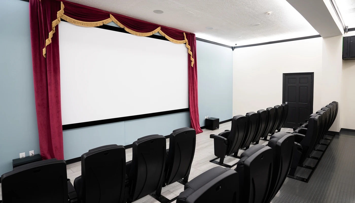 Small movie theater with rows of black chairs.