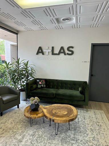 A reception area with a green couch, wooden tables, and a logo on the wall.