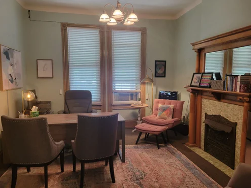Office with desk, chairs, books, and natural light