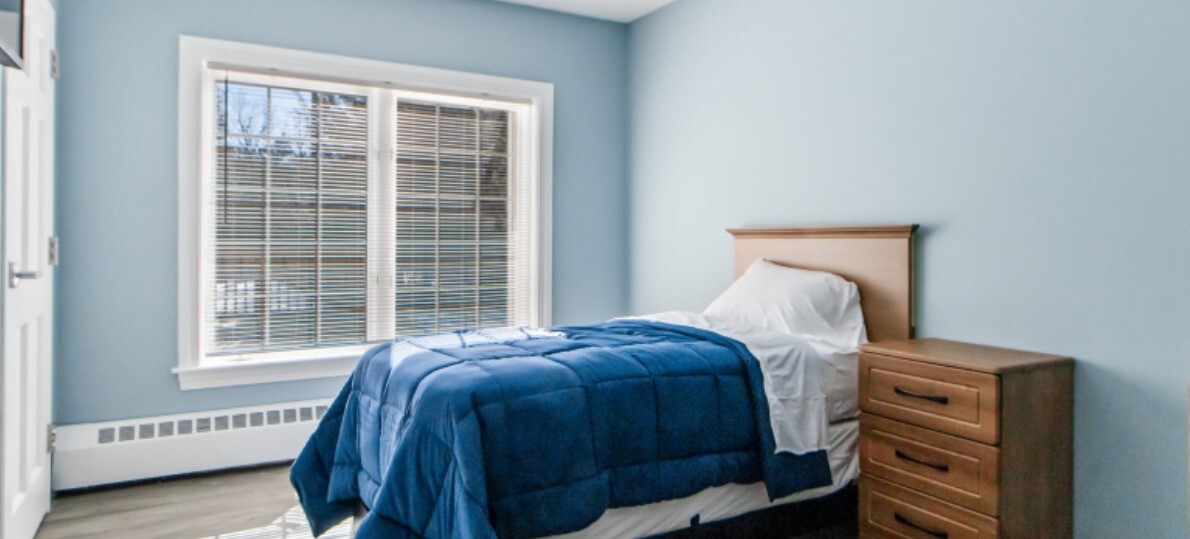 Bedroom with a bed and a wooden nightstand next to it.