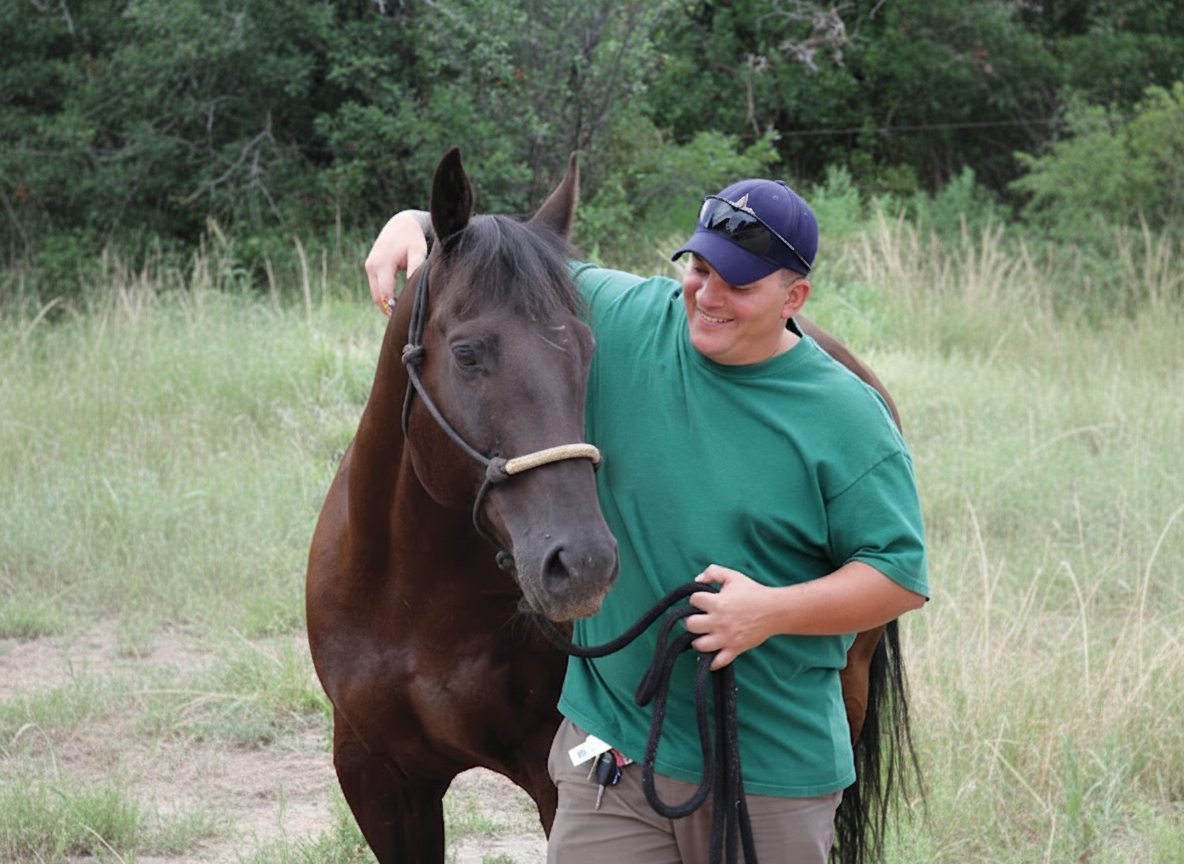 Person smiling while standing next to a horse outdoors.