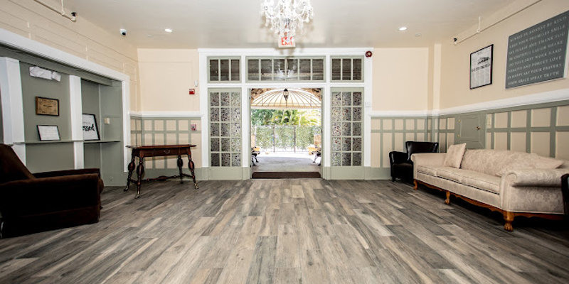  A bright and spacious entryway with elegant flooring, comfortable seating, and a chandelier, leading to a welcoming outdoor area.