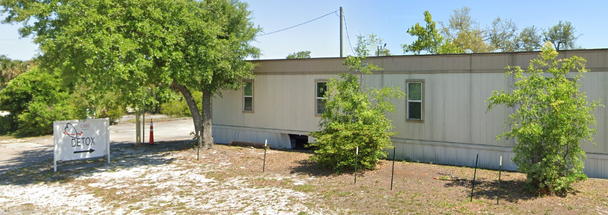 Single-story modular clinic building with trees and a CARE Detox sign