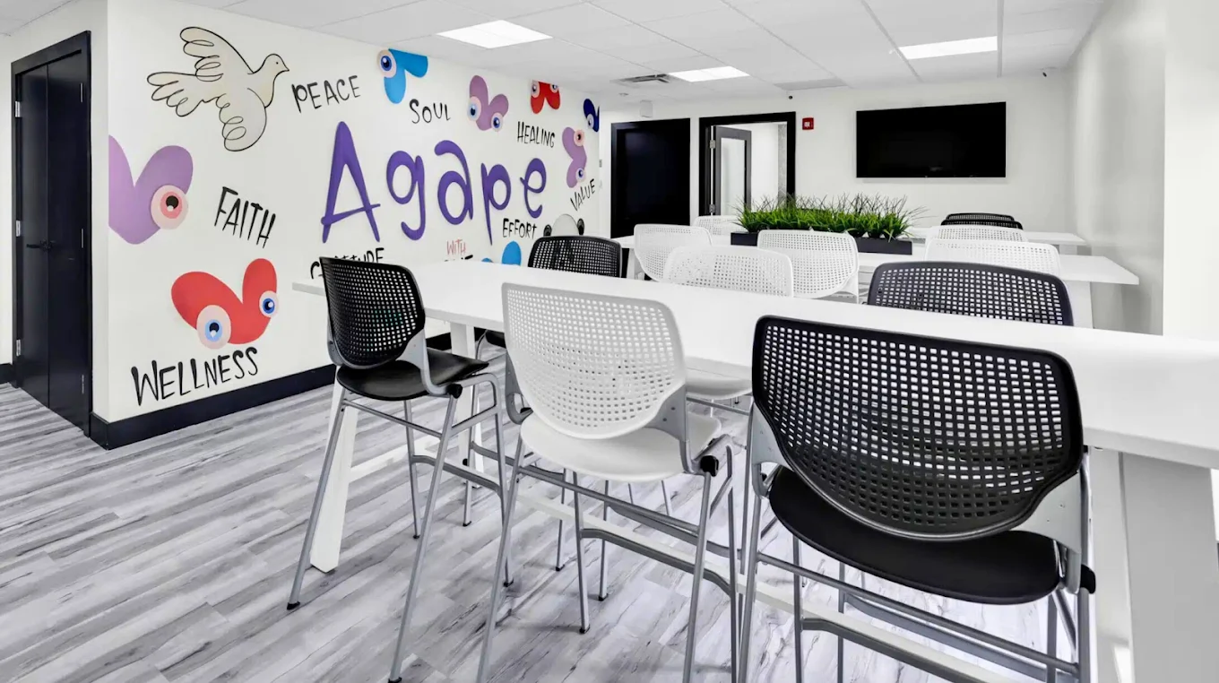 Group therapy room with tables, chairs, and TV