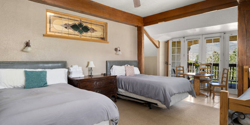  A cozy room with two plush beds, rustic wooden beams, and a private balcony offering a scenic mountain view. Inviting and tranquil setting.