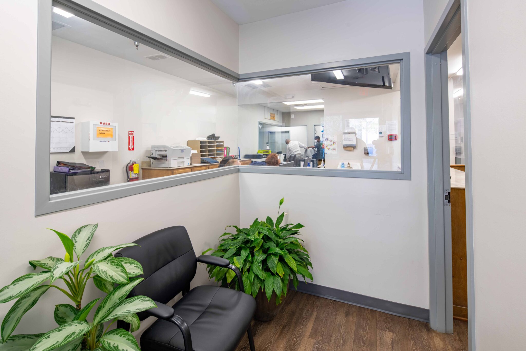 Waiting area with sofa, plants, and reception window
