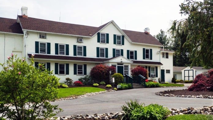 White colonial-style rehab center with manicured landscaping