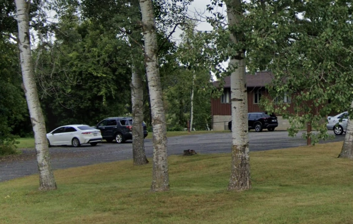 Tree-lined grounds with facility building and parking