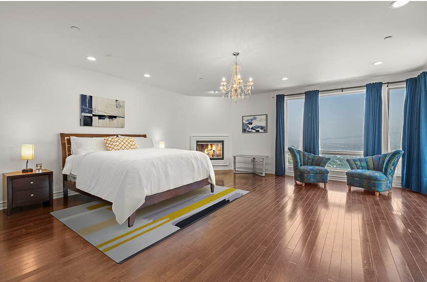 Bright bedroom with fireplace, chandelier, and ocean view windows