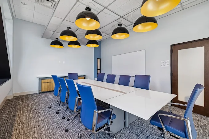 Large conference room with a long table and modern blue office chairs.