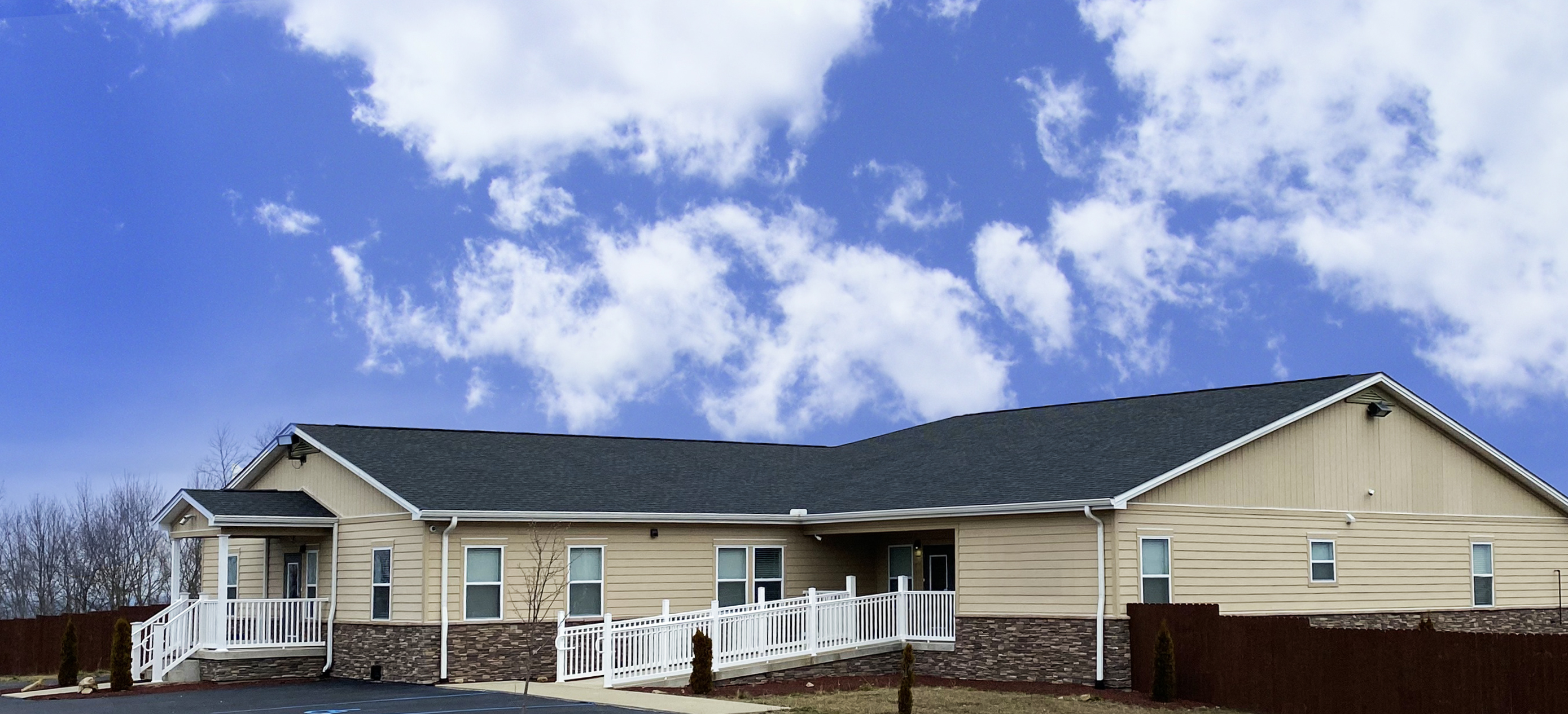 Beige single-story building with white ramps and a dark roof