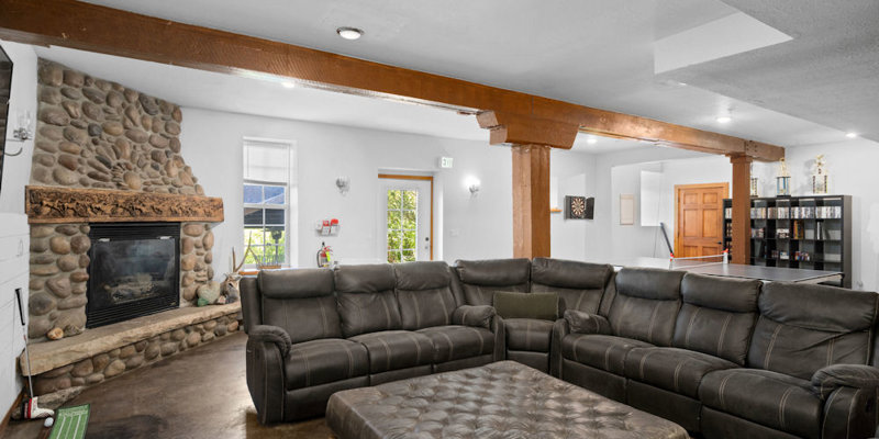 A warm, inviting lounge area featuring plush leather seating, a cozy stone fireplace, and rustic wooden beams, perfect for relaxation.