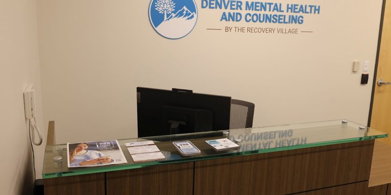 A welcoming front desk with brochures neatly arranged, featuring a sign that reads "Denver Mental Health and Counseling by The Recovery Village."