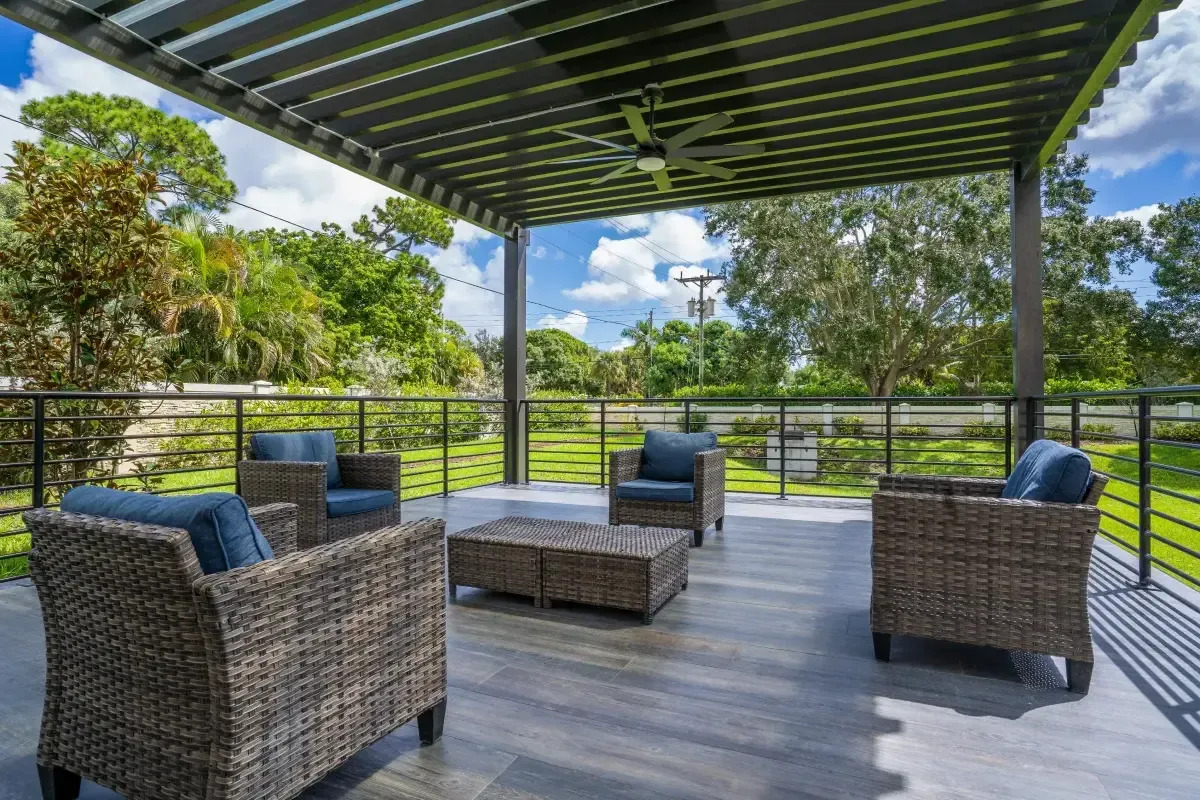 Covered patio with wicker seating overlooking greenery.