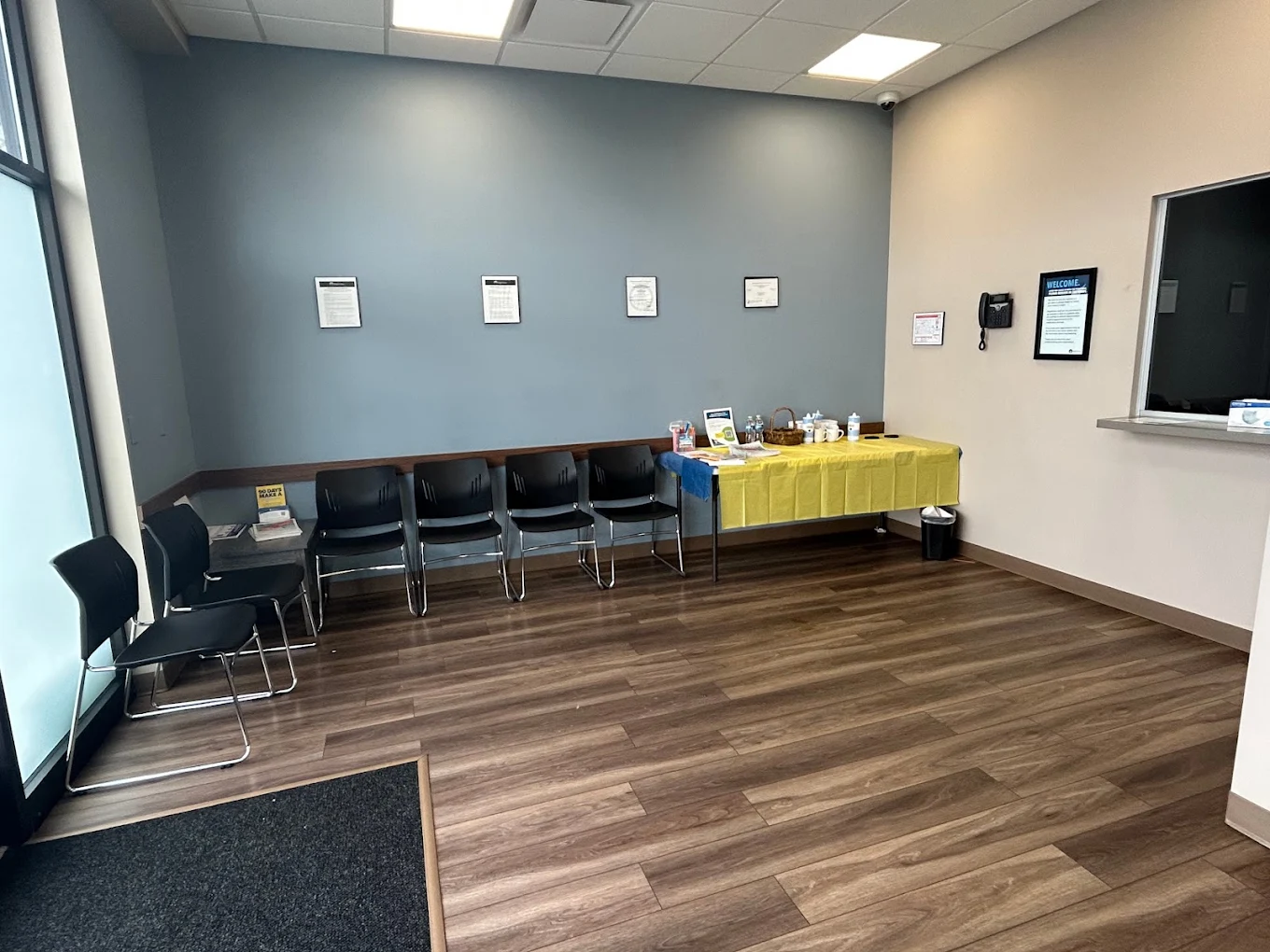 BrightView Health Winchester lobby with black waiting chairs, wood-look flooring, reception window, and refreshment table
