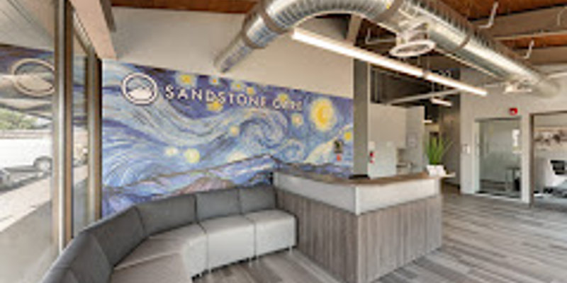 A bright, welcoming lobby with a curved gray sofa, modern reception desk, and a mural of a starry night sky on the wall behind.