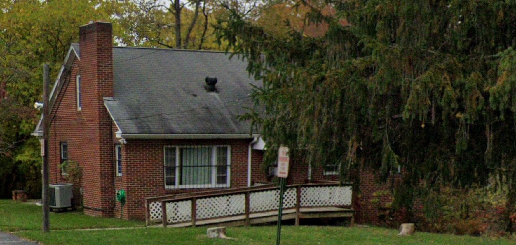 Street view of Metwork Health Services, a charming brick building surrounded by trees in a peaceful setting.