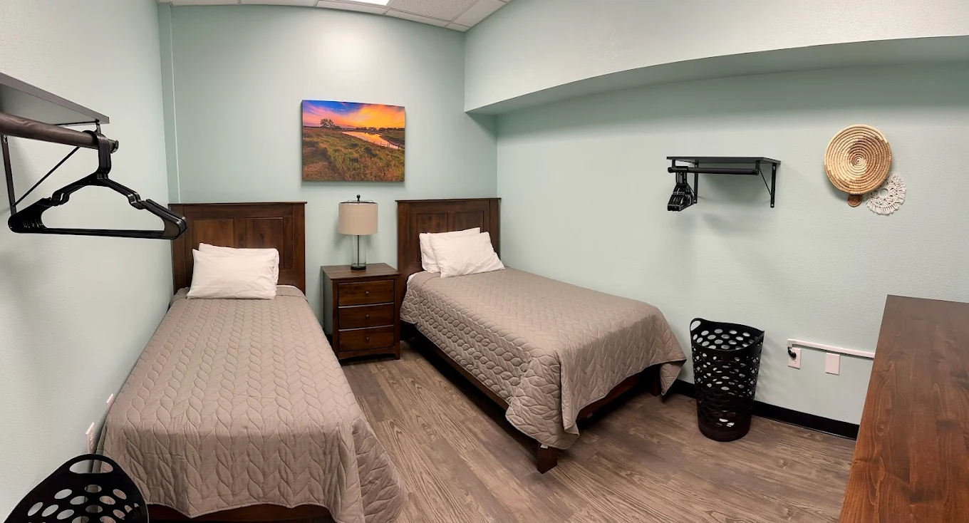 Two twin beds with gray bedding and a nature-themed wall art in a residential room