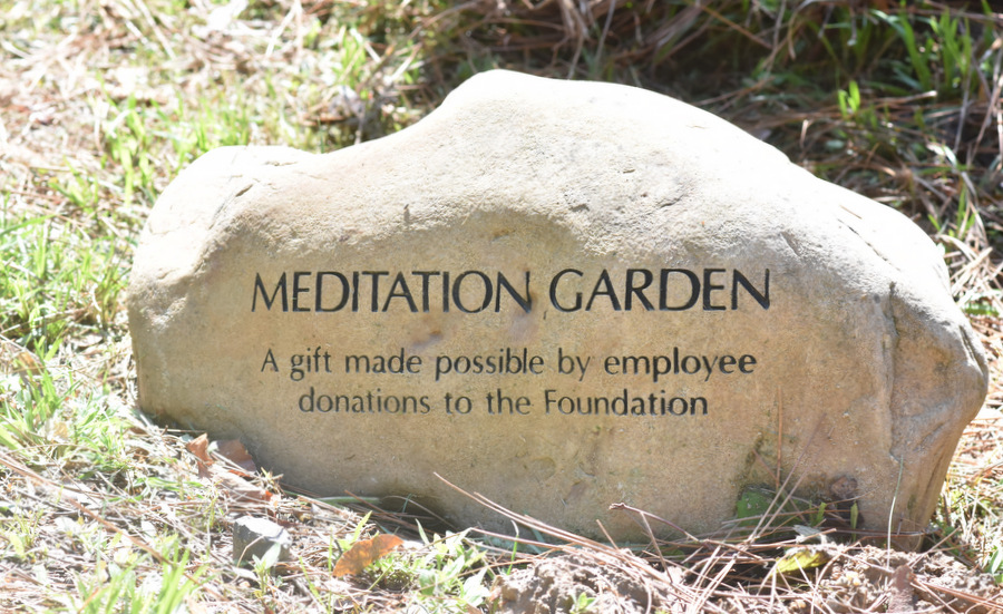 Engraved meditation garden stone surrounded by greenery