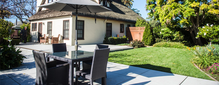 Patio table with umbrella near garden and house