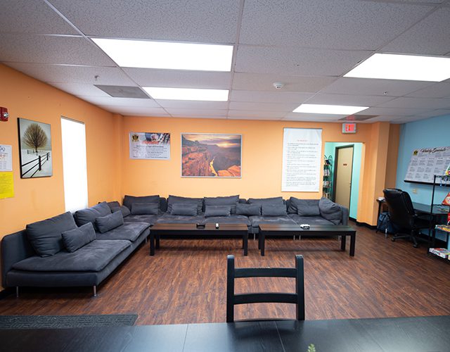 Orange-walled lounge with long black sofas and posters