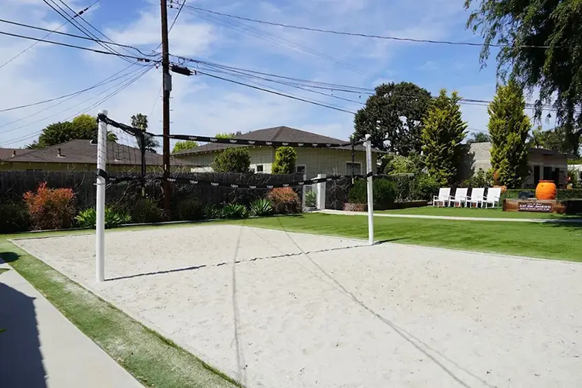 Sand volleyball court with lawn seating and trees around