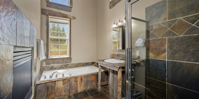 A rustic bathroom featuring slate tiles, a cozy jacuzzi tub, and natural wood accents, creating a warm and relaxing atmosphere.