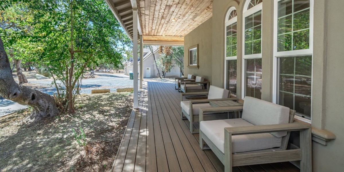 Covered porch with cushioned chairs facing the wooded property.