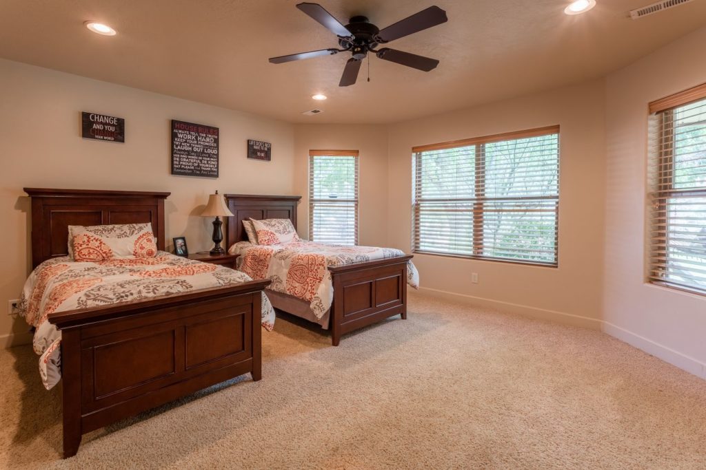 Shared bedroom with two wooden beds and large corner windows.
