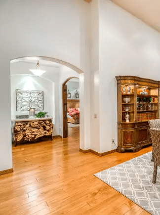 Residential-style interior with hardwood flooring, arched doorway, decorative cabinetry, and furnishings