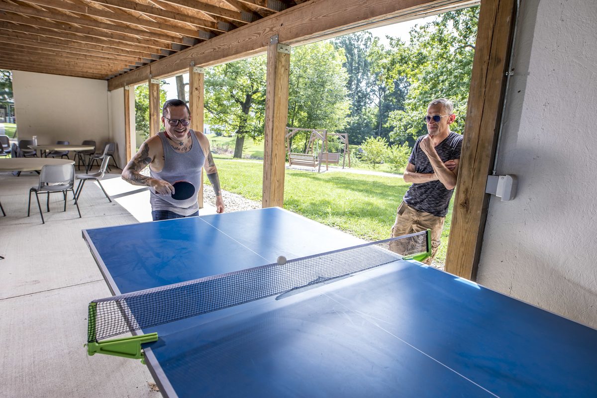 Residents play ping-pong on covered patio overlooking lawn
