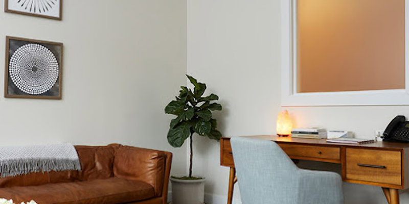 Warm and inviting office space featuring a leather couch, modern desk, and cozy decor, including a salt lamp and indoor plant.