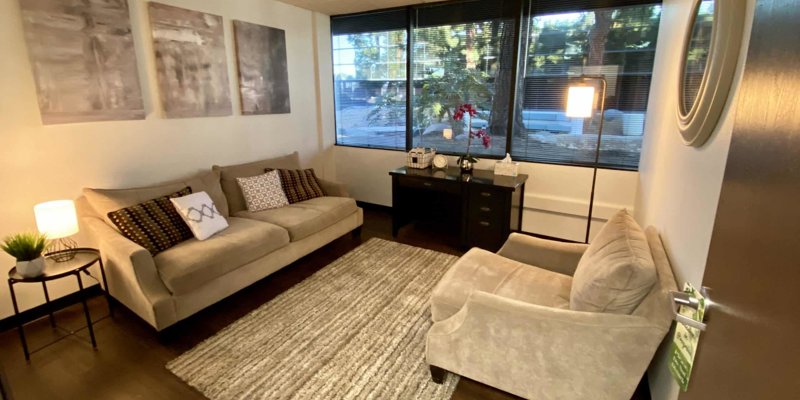 A cozy, private office space with soft lighting, comfortable beige sofas, a rug, and decorative accents creating a calming atmosphere.