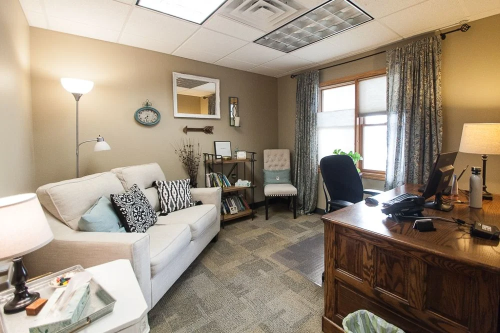 Cozy therapy office with sofa, desk, and window light