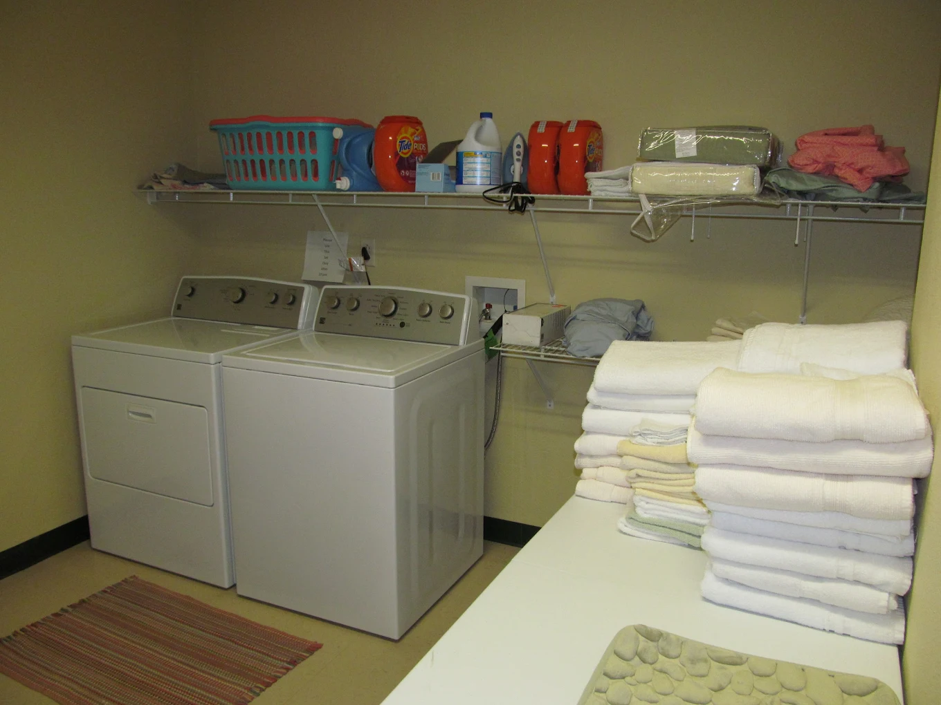 On-site laundry room with washer, dryer, and folded linens